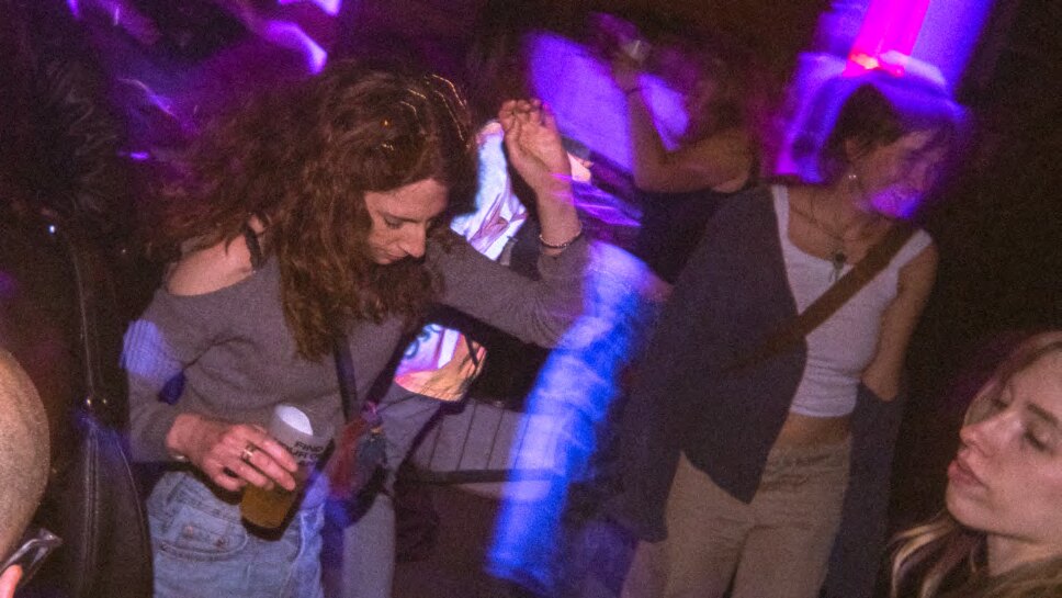 La gente che balla sotto le luci viola a una serata DMHertz al Bloom